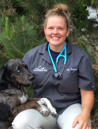 Dr. Sarah smiles with a dog in scrubs at a dental practice in Cañon City, Colorado.