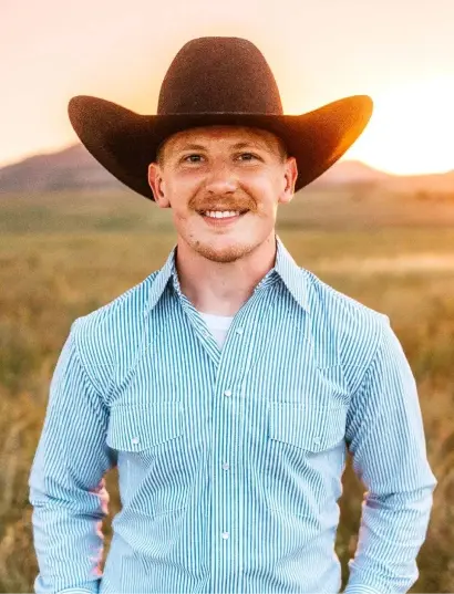 Dr. Schroder smiling in a blue striped shirt and cowboy hat outdoors in Cañon City.