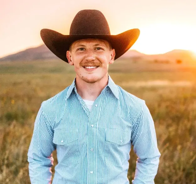 Dr. Wyatt Schroder smiling in a blue striped shirt and cowboy hat outdoors.