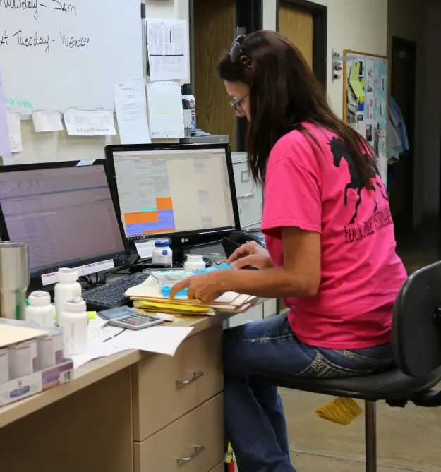 Dental office staff member working at desk with computers to manage patient financial options.