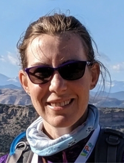 Dr. Nicodemus smiling outdoors in sunglasses with a mountain landscape in the background