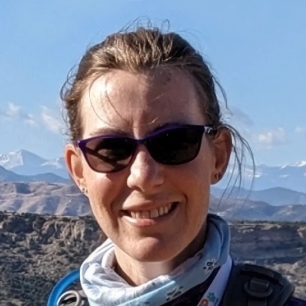 Dr. Nicodemus smiling outdoors in sunglasses with a mountain landscape in the background